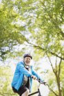 Ritratto fiducioso uomo anziano attivo in sella alla bici nel parco — Foto stock