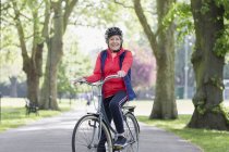 Portrait confident active senior woman riding bike in park — Stock Photo