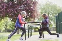 Активные старшие бегуньи, растягивающие ноги в парке — стоковое фото