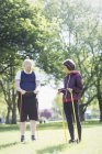 Active senior couple exercising, stretching with resistance bands in sunny park — Stock Photo