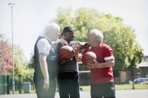 Активные старшие друзья играют в баскетбол в солнечном парке — стоковое фото