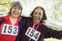 Porträt lächelnd, selbstbewusste aktive Seniorinnen, die in Wärmedecke gehüllt das Rennen beenden — Stockfoto