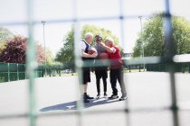 Активные старшие друзья играют в баскетбол в солнечном парке — стоковое фото