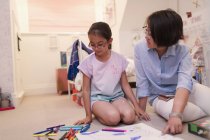 Mother and daughter coloring on bedroom floor — Stock Photo
