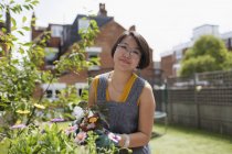 Retrato sorridente mulher jardinagem no quintal ensolarado — Fotografia de Stock