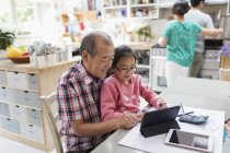 Grandfather and granddaughter using digital tablet in kitchen — Stock Photo