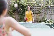 Mother and daughter playing table tennis in sunny backyard — Stock Photo