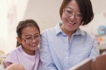 Smiling mother and daughter reading — Stock Photo
