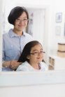 Mother fixing daughters hair in bathroom mirror — Stock Photo
