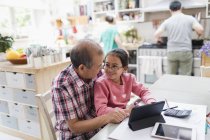 Grandfather and granddaughter using digital tablet at kitchen table — Stock Photo