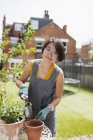 Retrato sorridente mulher jardinagem, vasos de flores no quintal ensolarado — Fotografia de Stock