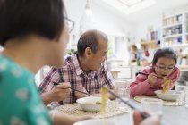 Família de várias gerações comendo macarrão com pauzinhos à mesa — Fotografia de Stock