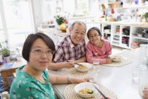 Portrait joyeuses nouilles de famille multi-générations avec baguettes à table — Photo de stock