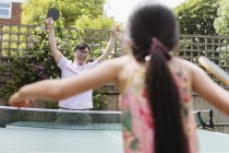 Exuberant father and daughter playing table tennis — Stock Photo