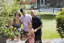 Портрет, улыбающийся многодетному семейному садоводству, цветочные горшки в солнечном дворе — стоковое фото