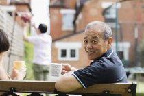 Porträt lächelnder älterer Mann trinkt Tee mit Familie im Hof — Stockfoto
