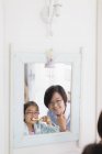Mutter beobachtet Tochter beim Zähneputzen im Badezimmerspiegel — Stockfoto