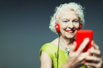 Пожилая женщина с наушниками и mp3-плеером, слушая музыку — стоковое фото