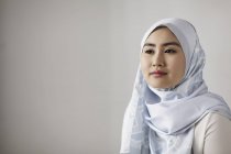 Portrait jeune femme sereine en hijab de soie bleue détournant les yeux — Photo de stock
