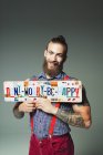 Portrait confident hipster man holding  Dont Worry Be Happy  license plates — Stock Photo