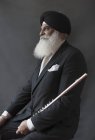 Portrait serious, well-dressed senior man in turban holding flute — Stock Photo