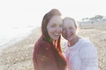 Retrato sorrindo, casal lésbico afetuoso na praia ensolarada — Fotografia de Stock