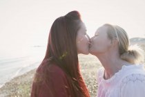 Casal lésbico afetuoso beijando na praia ensolarada — Fotografia de Stock