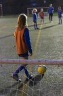 Дівчина-футболіст тренується на полі вночі — стокове фото
