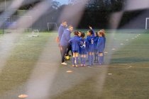 Entraîneurs de football et équipe de football fille parlant sur le terrain — Photo de stock