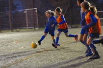 Equipe de futebol meninas praticando em campo à noite — Fotografia de Stock