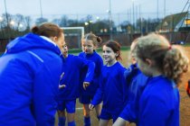 Equipe de futebol meninas ouvindo treinador em amontoar — Fotografia de Stock