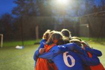 Mädchenfußballmannschaft kauert nachts auf dem Feld — Stockfoto