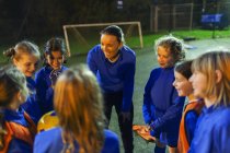 Squadra di calcio femminile ascoltando allenatore sul campo di notte — Foto stock
