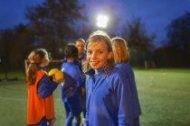 Портрет усміхнений, впевнена дівчина футболіст на полі вночі — стокове фото