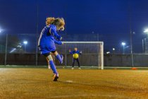 Chica futbolista pateando la pelota hacia el gol - foto de stock