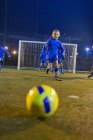 Menina jogador de futebol praticando em campo à noite — Fotografia de Stock