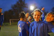 Portrait confiant, fille heureuse joueurs de soccer sur le terrain la nuit — Photo de stock