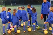 Футбольная команда девочек слушает тренеров на поле — стоковое фото