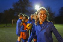Retrato entusiasta menina jogadores de futebol torcendo em campo à noite — Fotografia de Stock