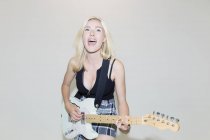 Ausgelassene junge Frau spielt E-Gitarre — Stockfoto