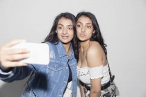 Teenage twin girls taking selfie with smart phone — Stock Photo