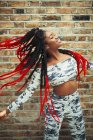 Unbekümmerte junge Frau in Tarnkleidung tanzt gegen Backsteinmauer — Stockfoto