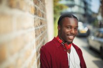 Portrait smiling, confident teenage boy with headphones on urban sidewalk — Stock Photo