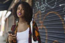 Mujer joven con teléfono inteligente en la acera urbana - foto de stock