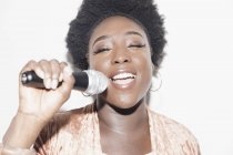 Young woman with microphone singing — Stock Photo
