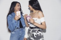 Смеющиеся сёстры-близнецы используют смартфоны — стоковое фото