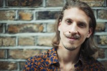 Porträt lächelnder, selbstbewusster junger männlicher Hipster mit Schnurrbart — Stockfoto