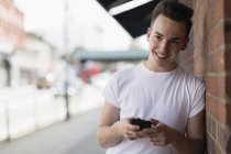 Ragazzo adolescente utilizzando smart phone sul marciapiede urbano — Foto stock
