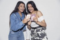 Сестрички-близнецы, использующие смартфоны — стоковое фото