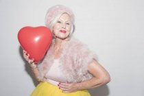 Ritratto donna anziana sicura di sé in pelliccia con palloncino a forma di cuore — Foto stock